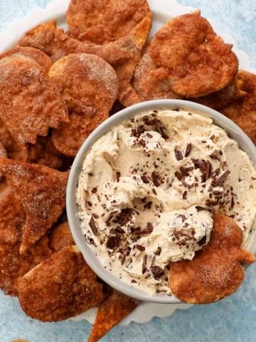 white cinnamon dip in a grey bowl with brown chips placed around it.