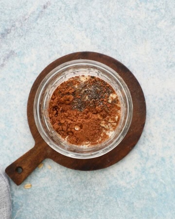 oats, cocoa powder and milk in a glass jar.