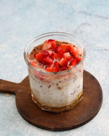 chopped strawberries, milk and oats in a glass jar.
