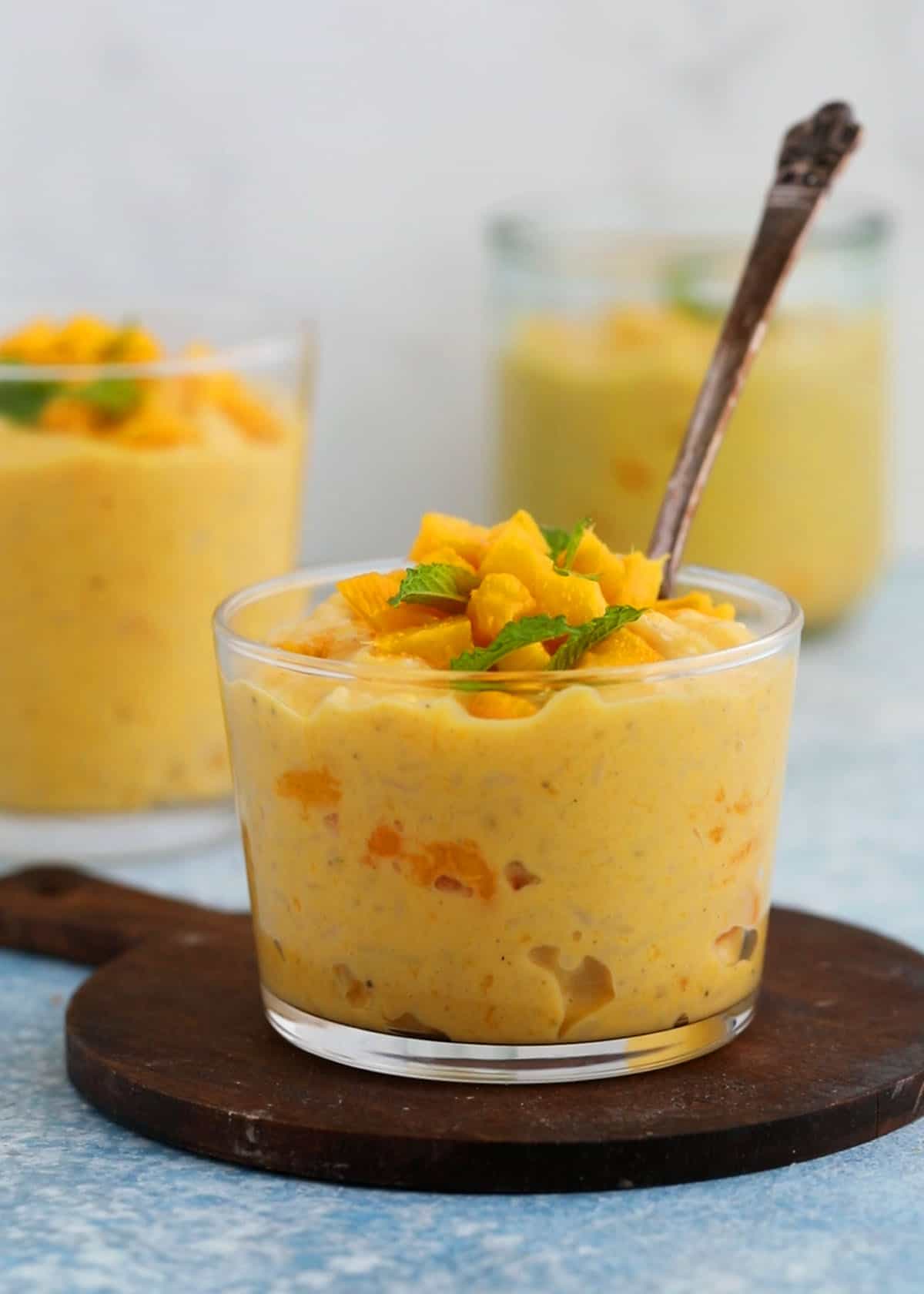 three glass jars filled with yellow colored mango rice pudding.