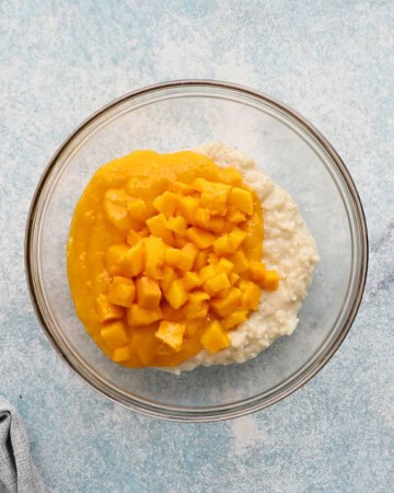 one glass bowl with cooked white rice, chopped mango and puree.