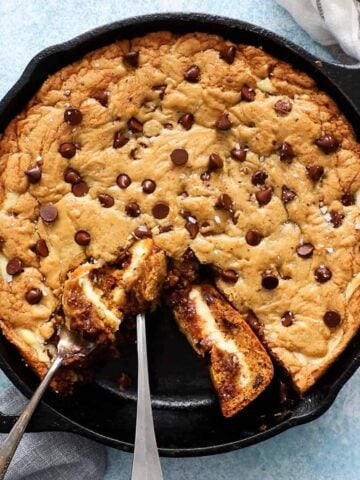 baked chocolate chip cookie in a black skillet along with two forks.