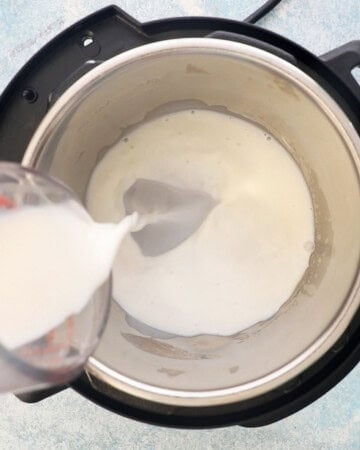 a hand pouring white milk into an instant pot. 