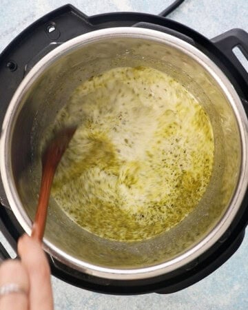 a hand stirring green liquid in an instant pot.