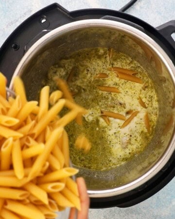 two hands duping raw penne pasta into an instant pot.