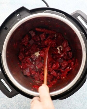 a hand sauteeing chopped beets in an instant pot.