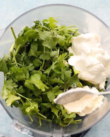 cilantro leaves and white sour cream in a food processor.