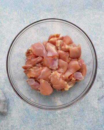 cut raw chicken chunks placed in a glass bowl.