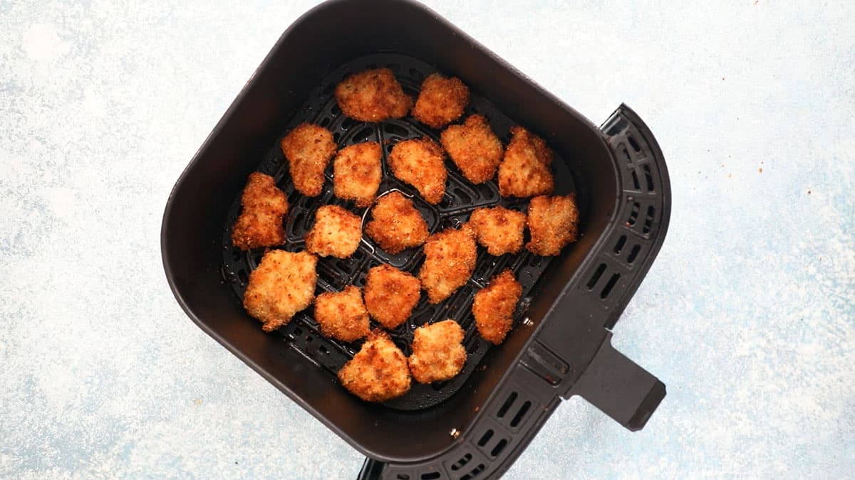 cooked chicken nuggets in an air fryer basket.