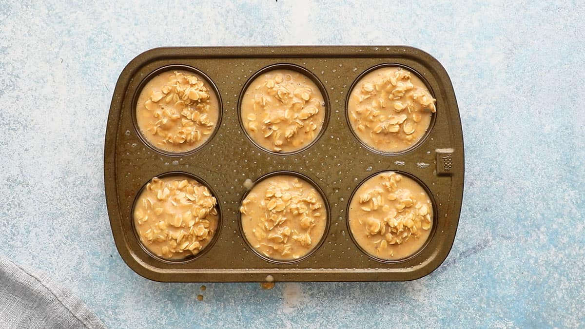 one 6 cup metal muffin pan filled with baked oatmeal batter.