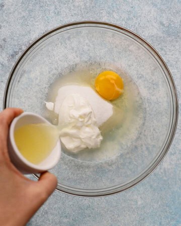 a hand pouring lemon juice into a large glass bowl.