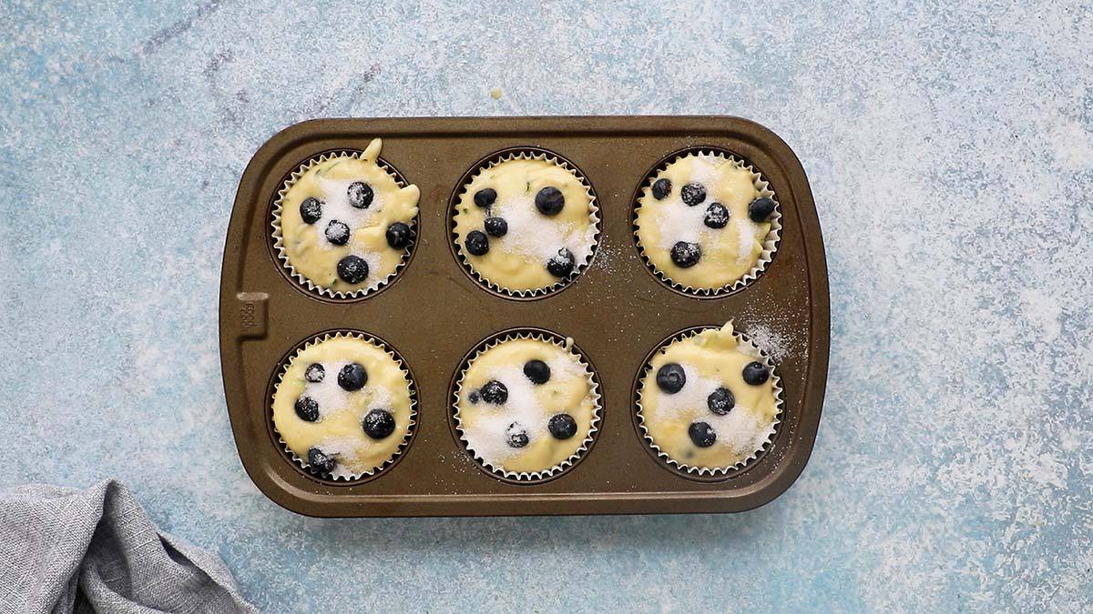 6 cup muffin pan filled with blueberry muffin batter.