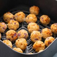 cooked chicken meatballs in an air fryer basket.