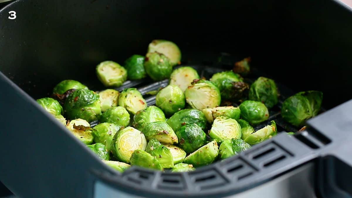 an air fryer basket with cooked brussels sprouts.