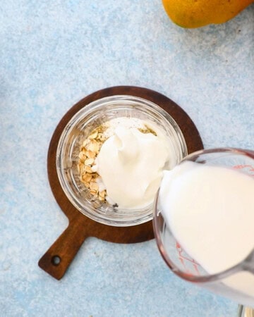 a hand pouring milk into a glass jar.