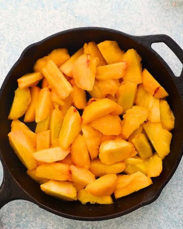 sliced peaches in a black skillet.