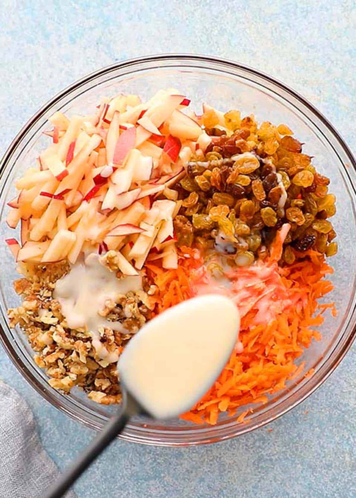 all carrot salad ingredients assembled in a glass bowl.