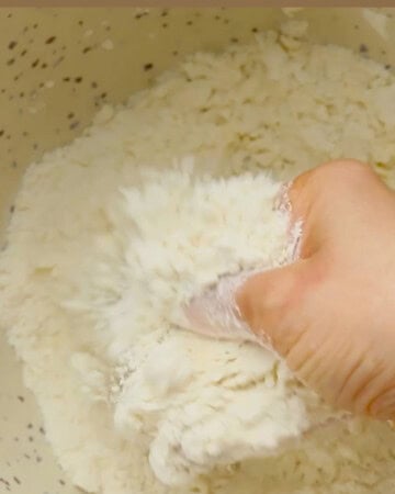 a hand mixing flour in a white bowl.