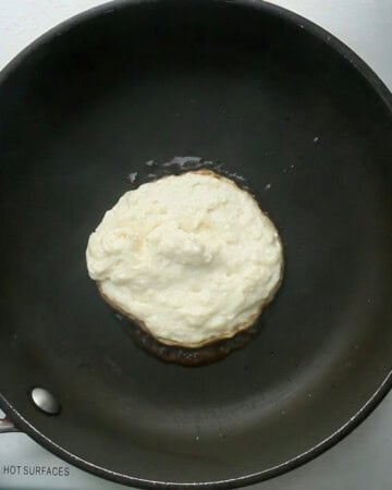 one pancake cooking in a black skillet.