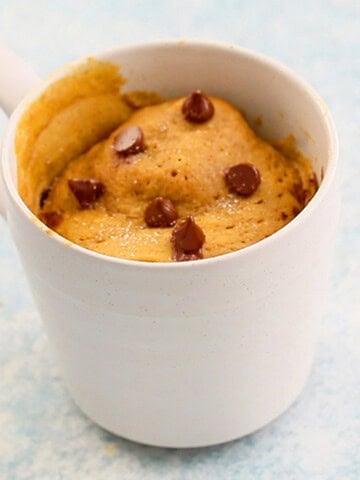 pumpkin cake topped with chocolate chips in a white mug.