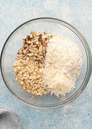 shredded coconut, oats, and sliced almonds in a glass bowl. 