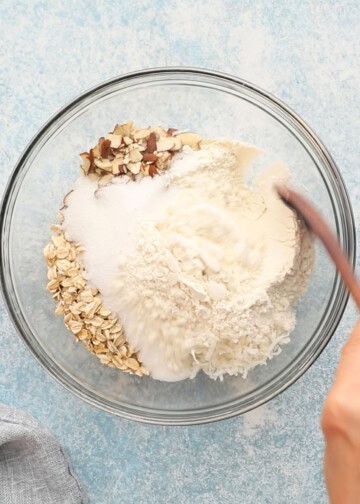 shredded coconut, oats, sugar and sliced almonds in a glass bowl. 