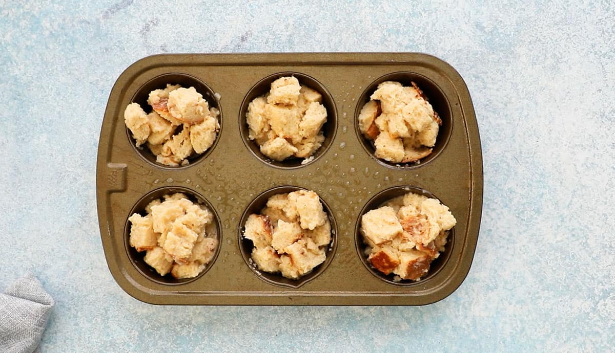 one 6 cup metal muffin pan with with french toast mixture ready to be baked. 