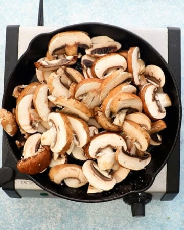 sliced mushrooms piled high in a black skillet.