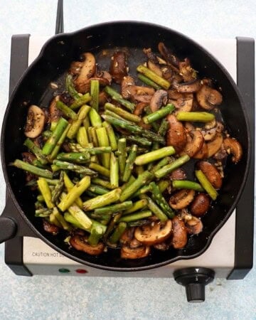 sauteed asparagus and mushrooms in a black skillet.