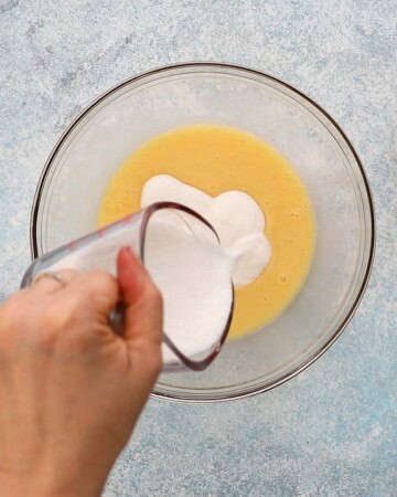 a hand pouring white milk into a large glass bowl.