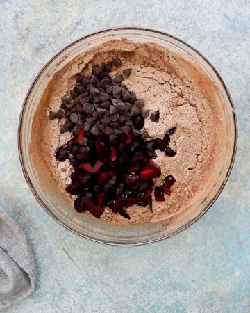 brown flour, chopped red cherries and chocolate chips in a large glass bowl.