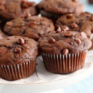 6 chocolate muffins placed on a white cake stand.