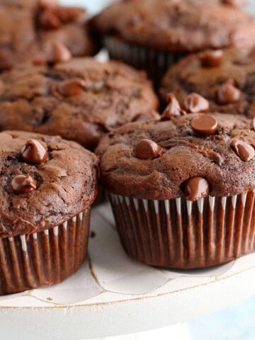 6 chocolate muffins placed on a white cake stand.