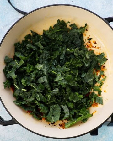 chopped green kale leaf placed in a large white skillet.