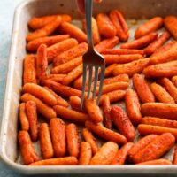 roasted baby carrots in a metal sheet pan along with a fork.