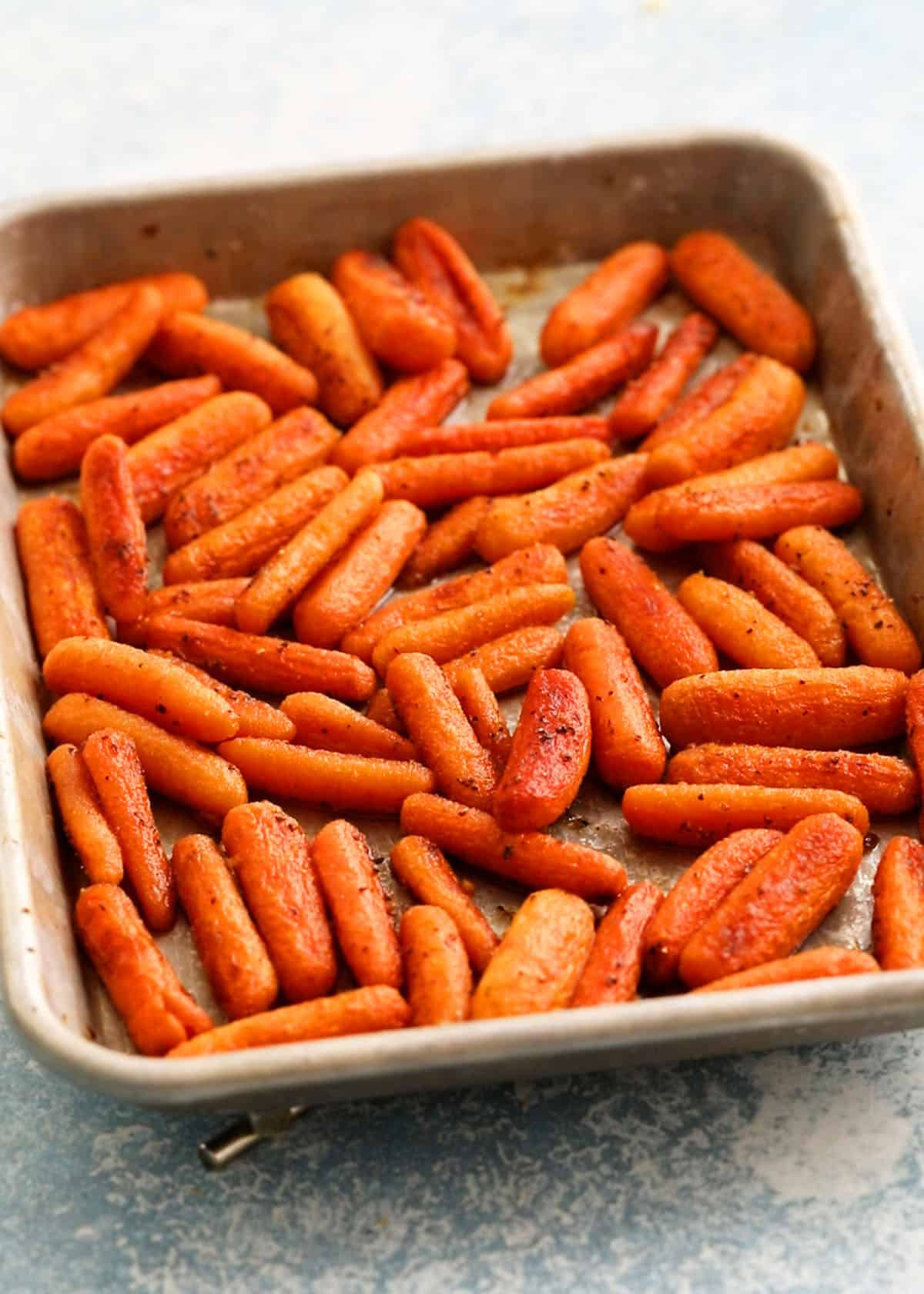 cooked orange baby carrots in a metal sheet pan.