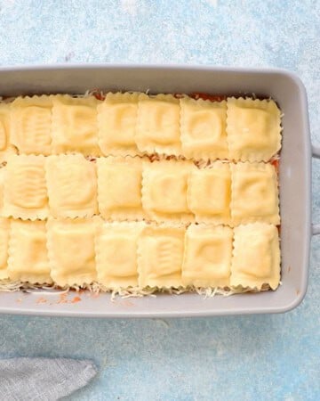 uncooked yellow ravioli pasta arranged in a grey baking dish.