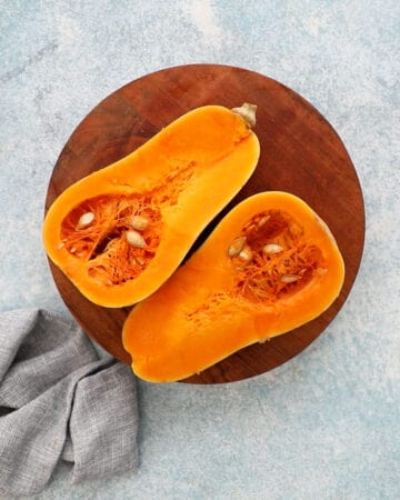 two cut butternut squash halves placed on a wooden board.