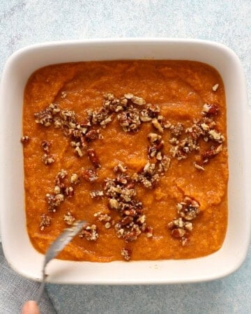 cooked orange butternut squash puree in a white ceramic square baking dish.