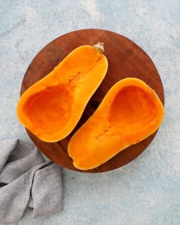 two cut butternut squash halves placed on a wooden board.