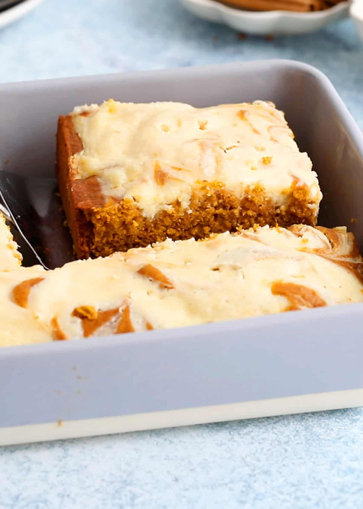 baked cream cheese topped pumpkin cake in a grey pan.