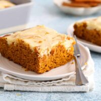 one slice of pumpkin cake topped with cream cheese in a white plate.