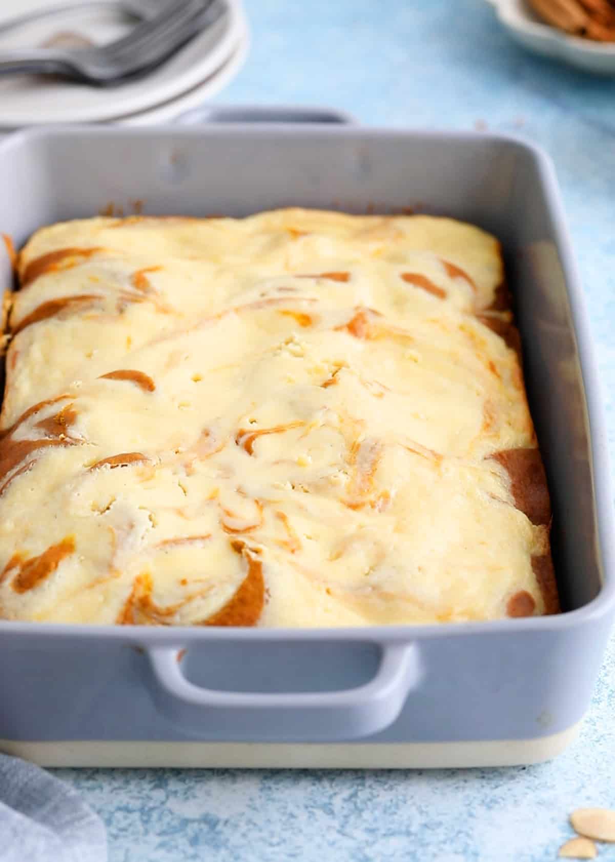 baked cream cheese topped pumpkin cake in a grey pan.